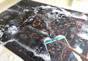 Cleaning a wool Chinese rug by brushing a woolsafe shampoo through the fibres whilst it is fully immersed in our rug cleaning pit