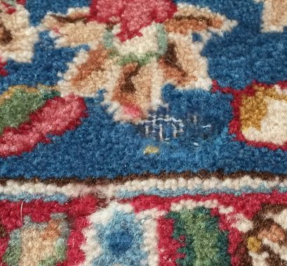 A Persian wool rug with damage caused by carpet moth