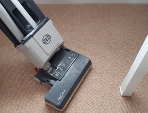 An upright vacuum cleaner being used on carpet