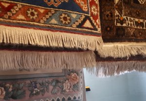 A couple of rugs hung up on a drying rack to allow them to dry out fully before treating the fringes